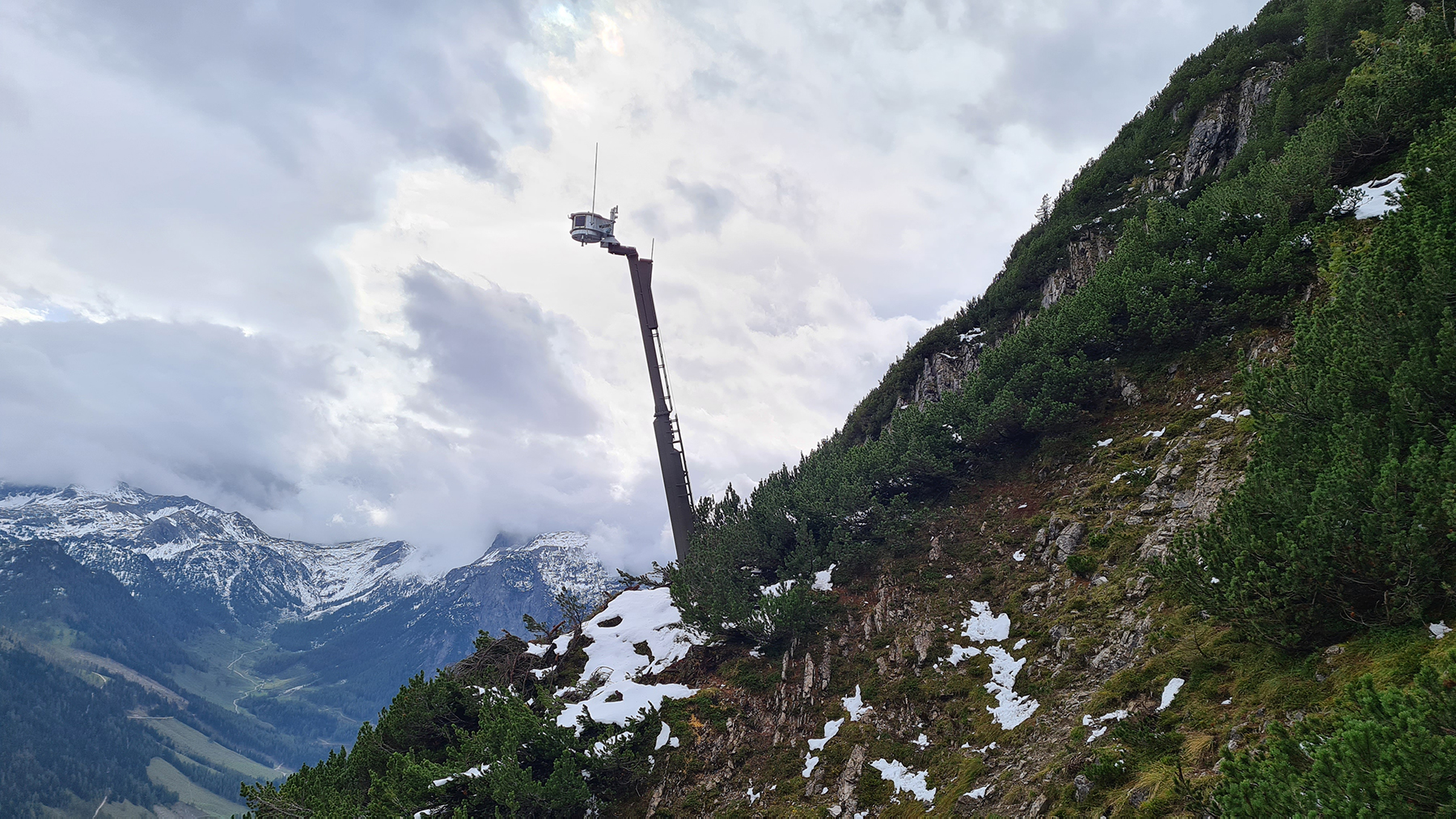Ein Lawinensprengmast mit Magazin an einem Abhang in den Bergen