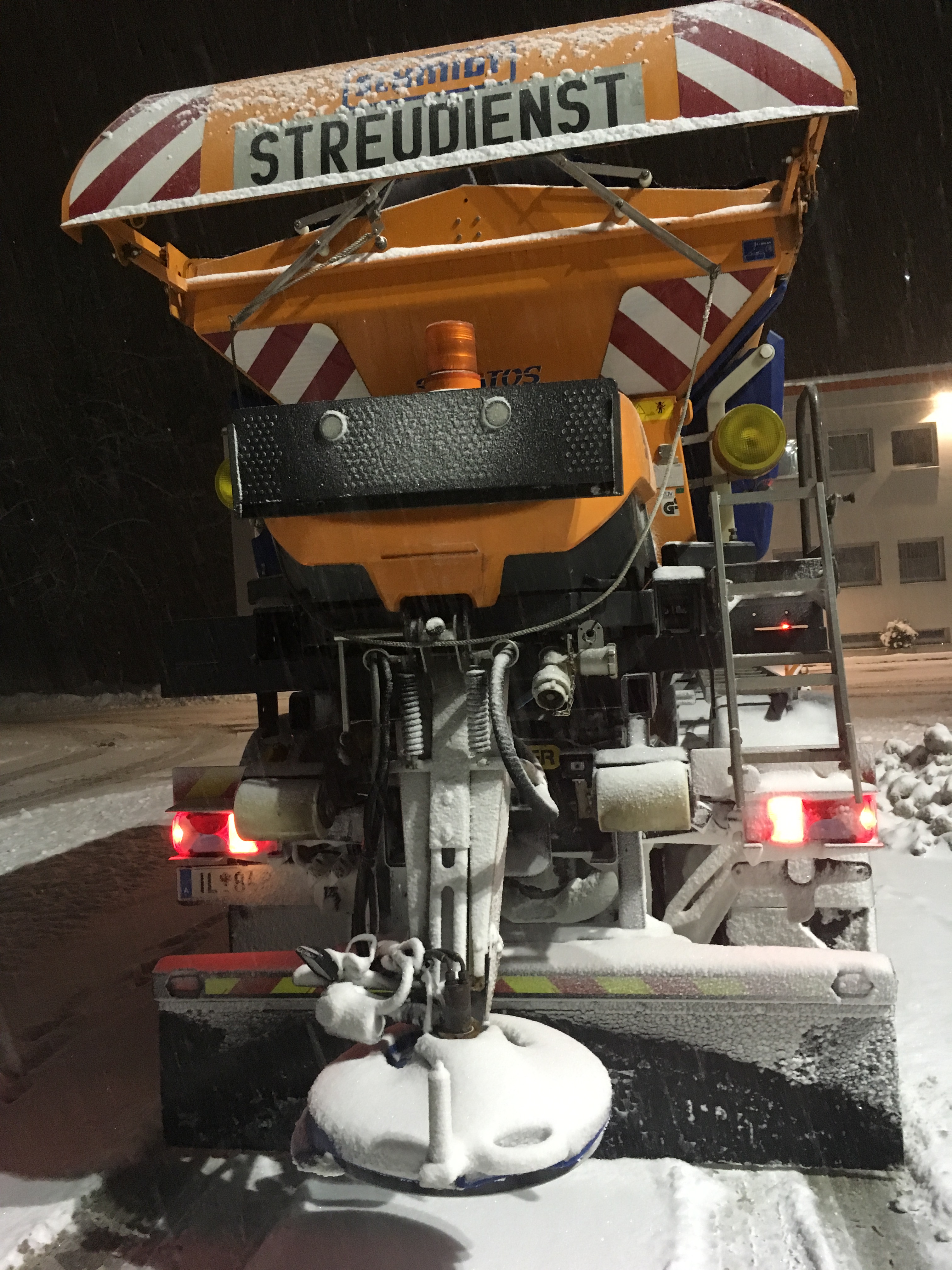 Oranger Lkw mit sieben Kubikmeter Fassungsvermögen für Trockensalz und 3.400 Liter Salzsole bei Nacht