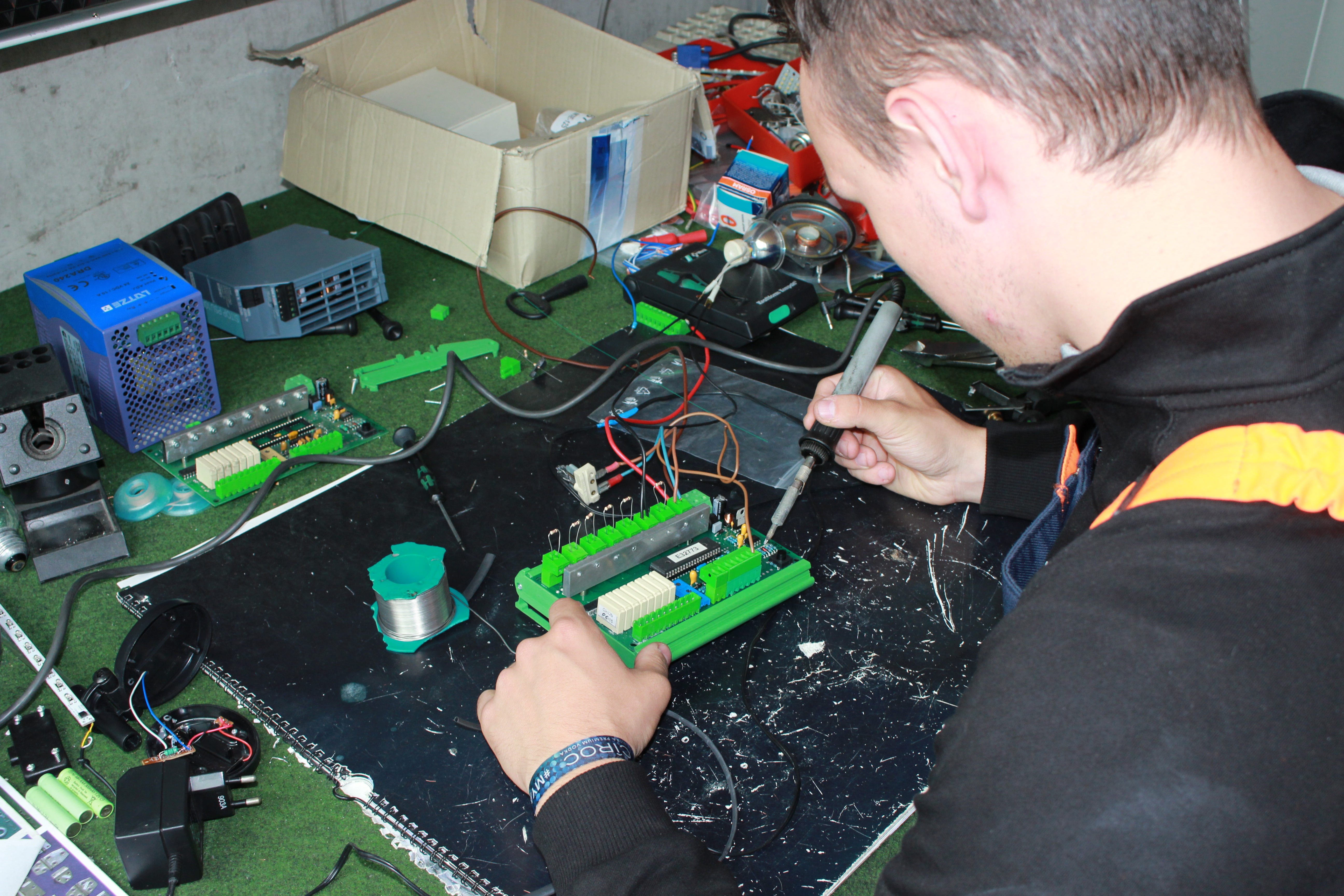 Ein Mann arbeitet mit einem Lötkolben an einer Steuerplatine