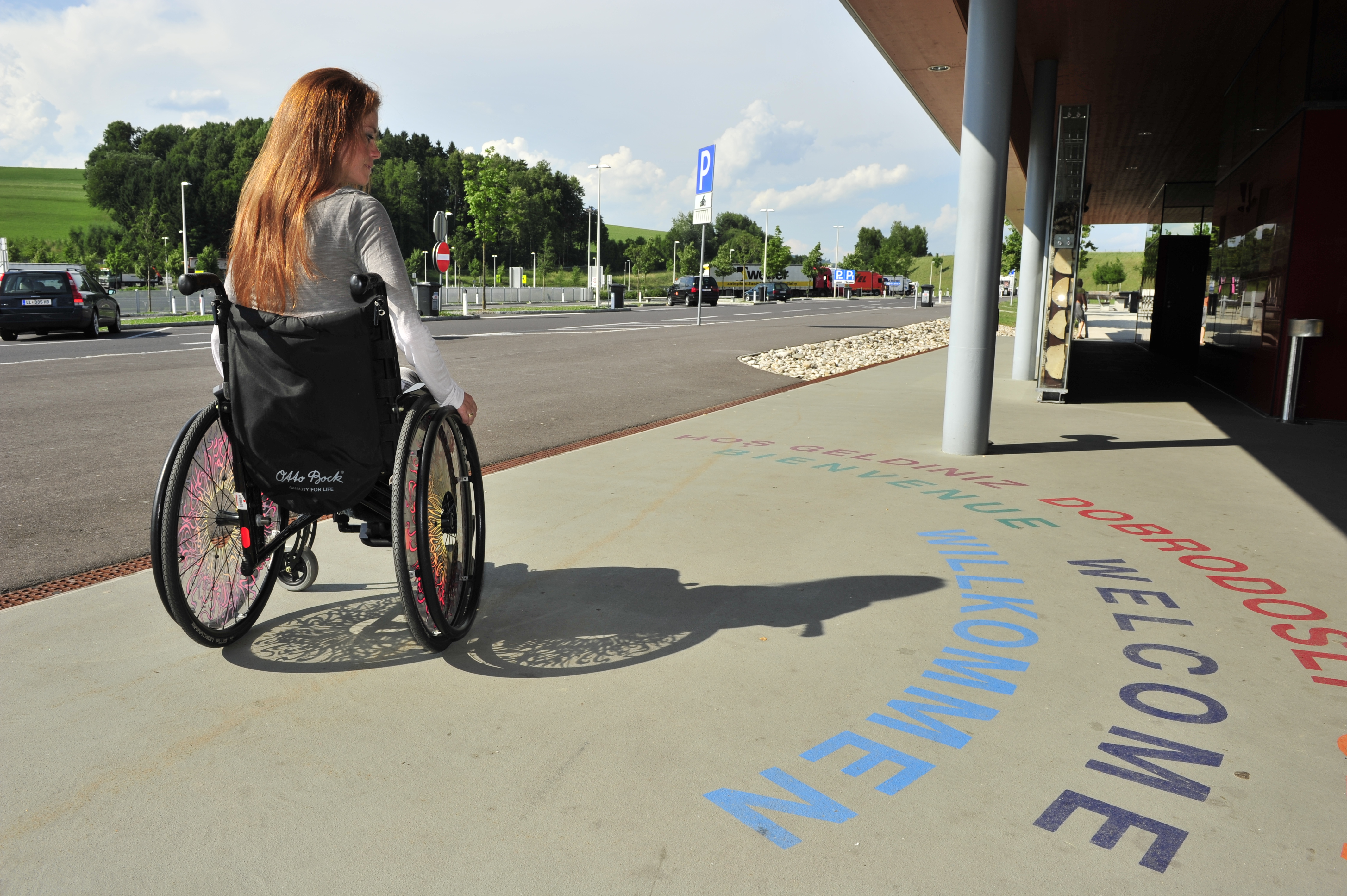 Junge Frau im Rollstuhl vor einem ASFINAG Rastplatz