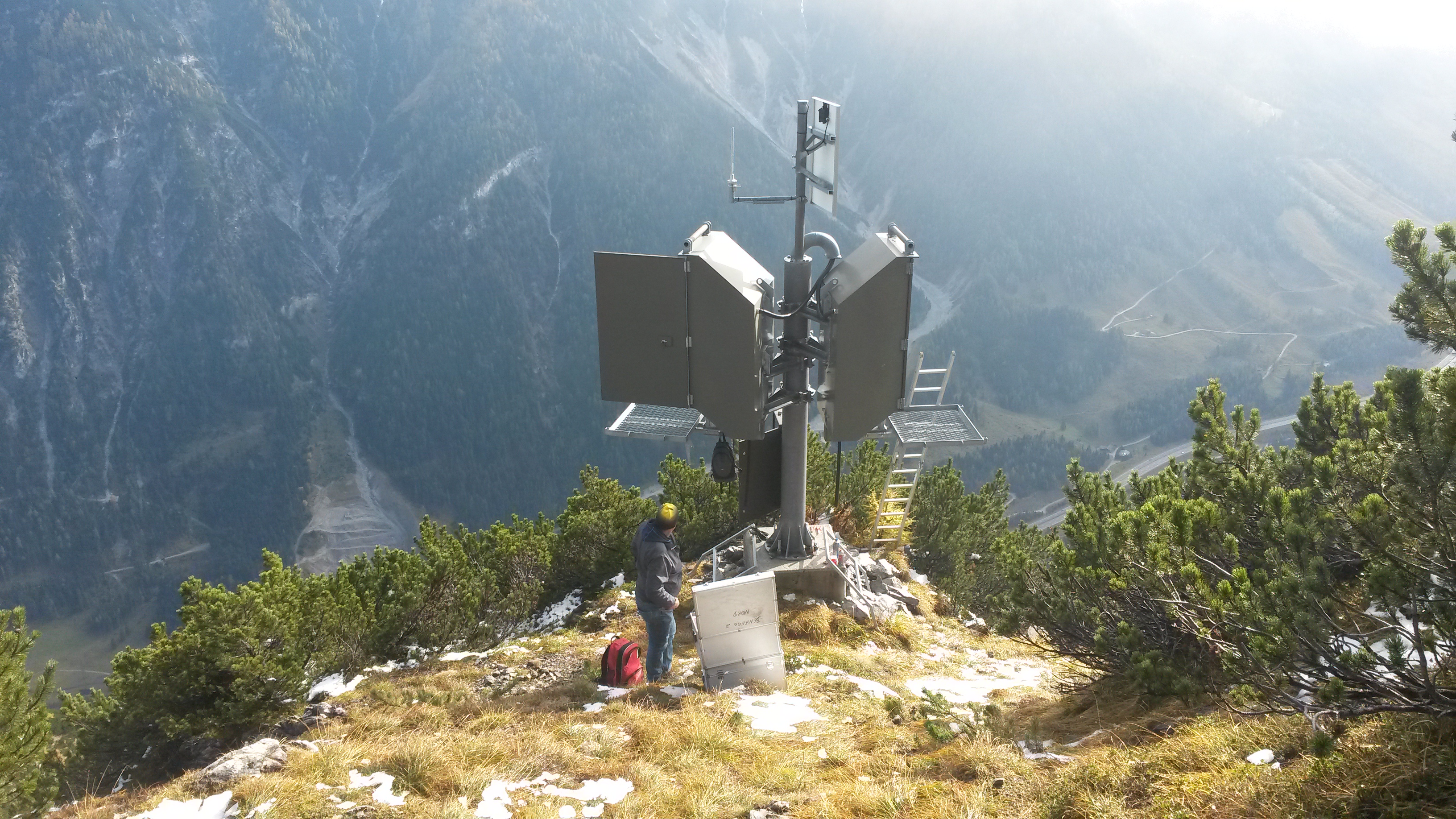 Eine Lawinensprenganlage an einem Abhang. Eine Person steht davor.
