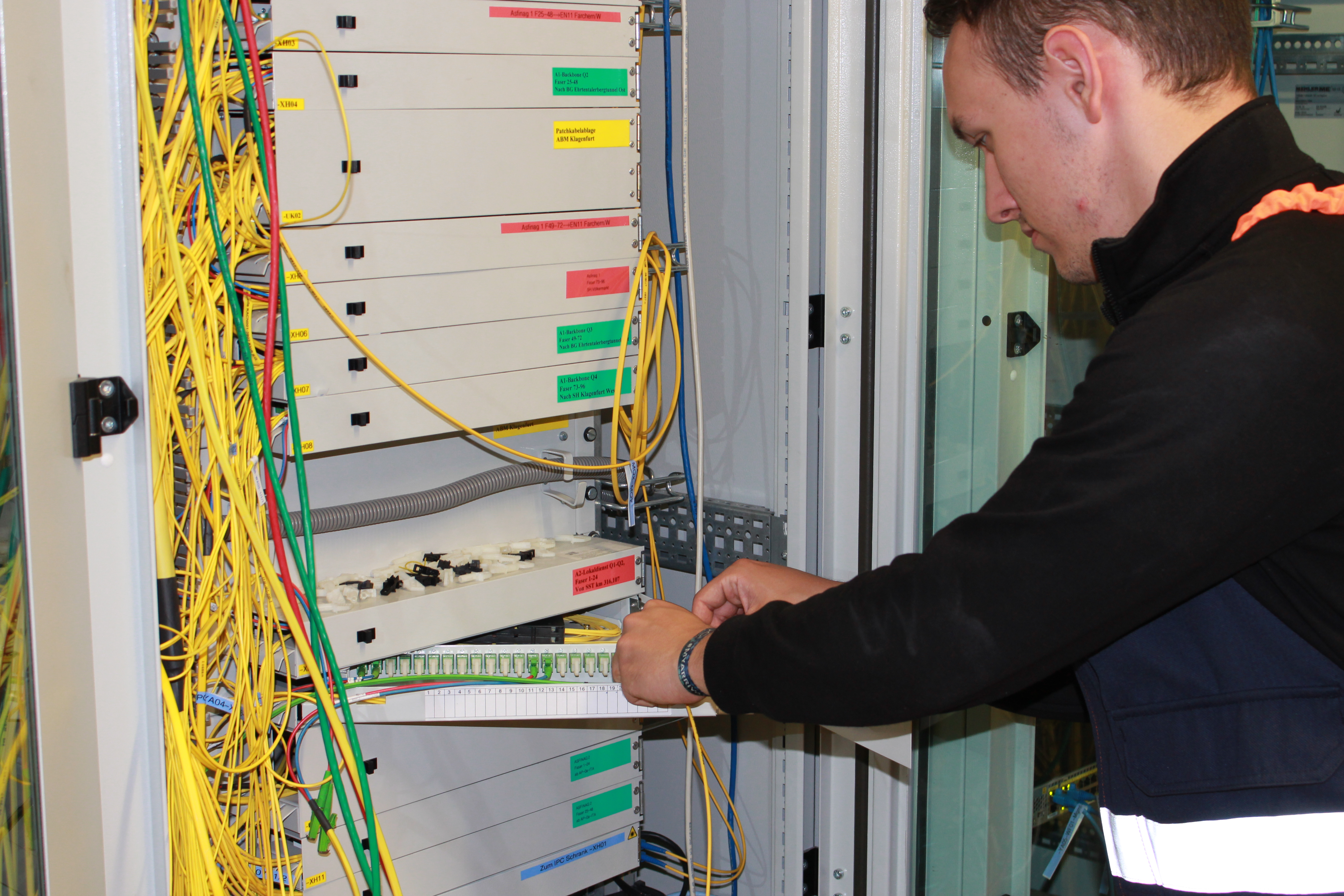 Ein Mann arbeitet an einem Kasten, in dem sich mehrere gelbe Kabel befinden, die auf kleiner Fächern herausragen