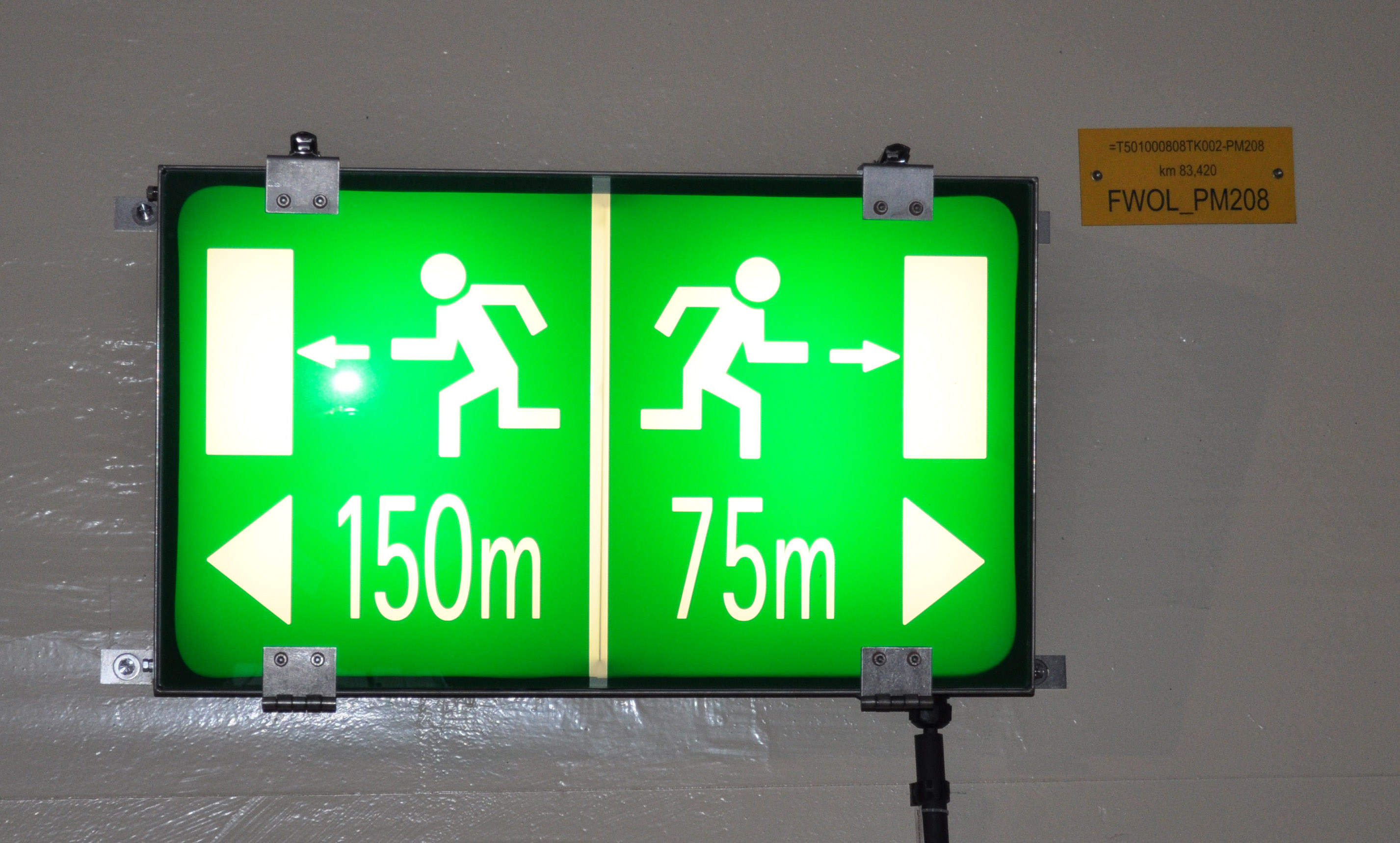 Grün/weiße Hinweistafeln zeigen die Distanz zum Fluchtweg an